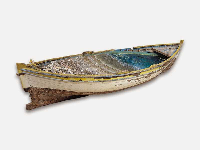 Stelios Gavalas sculpture of a traditional wooden fisherman's boat with a beach in the inside.